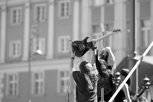 Dynamic black and white photo of musicians with guitars at an outdoor concert.