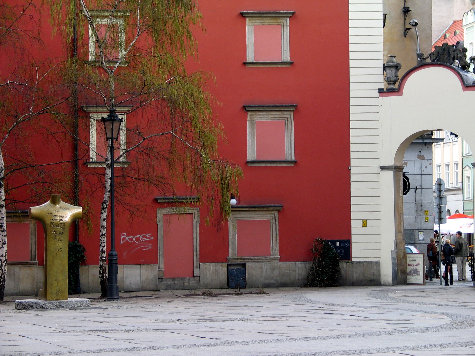 A vibrant urban setting featuring a red building, birch trees, and an archway in a town square.