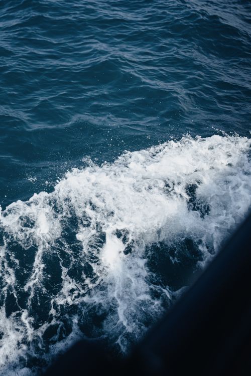 Free Close-up view of ocean waves creating foam on blue water surface, captured from above. Stock Photo