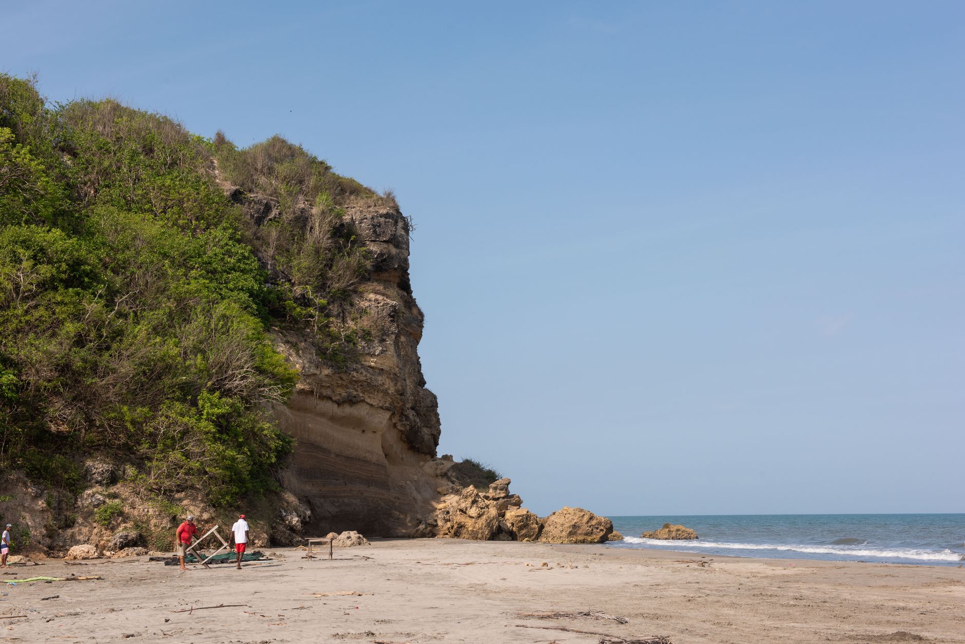 Coastal scene with a sandy beach, cliffs, and ocean waves in Cartagena, Colombia.