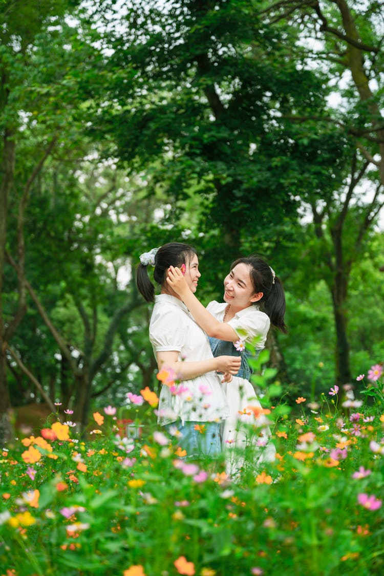 Woman Putting Flower Behind Friend Ear