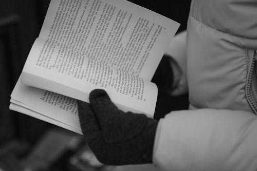Close-up of a Person Wearing a Jacket and Gloves Holding a Book 