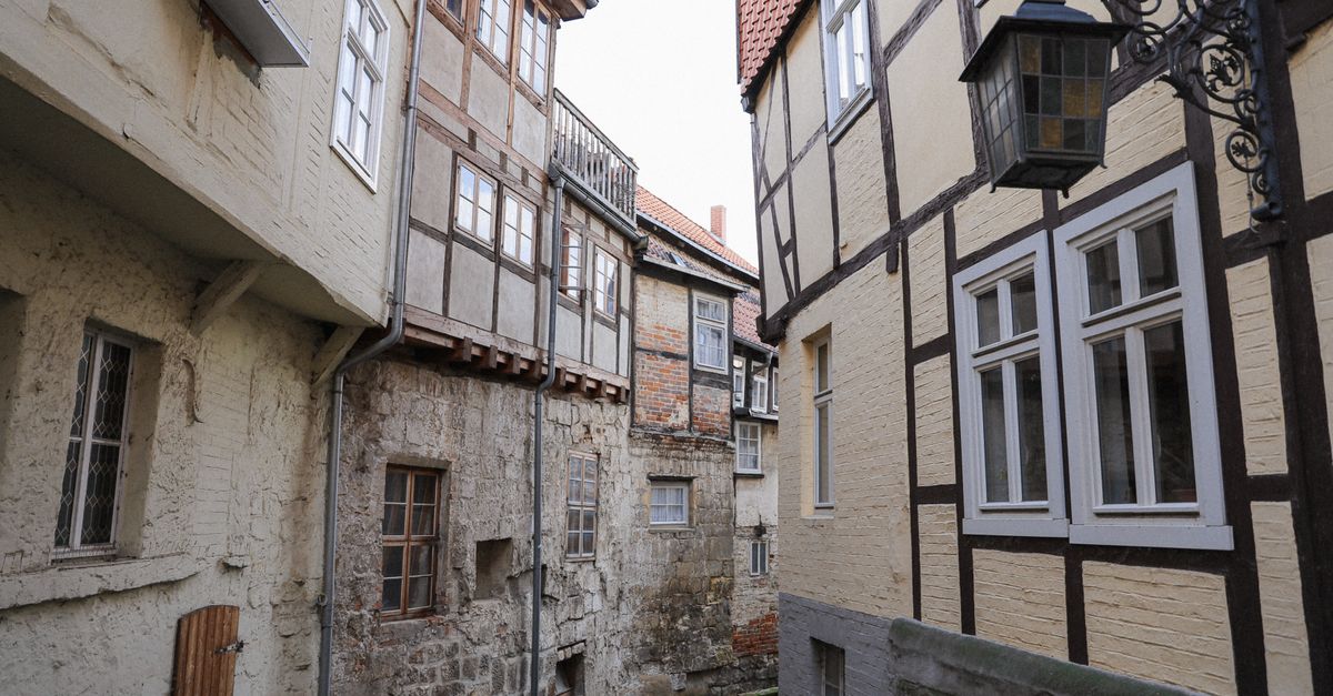 Historische Gasse in Quedlinburg mit UNESCO-Welterbe-Fachwerkhäusern und klassischer Straßenlaterne.