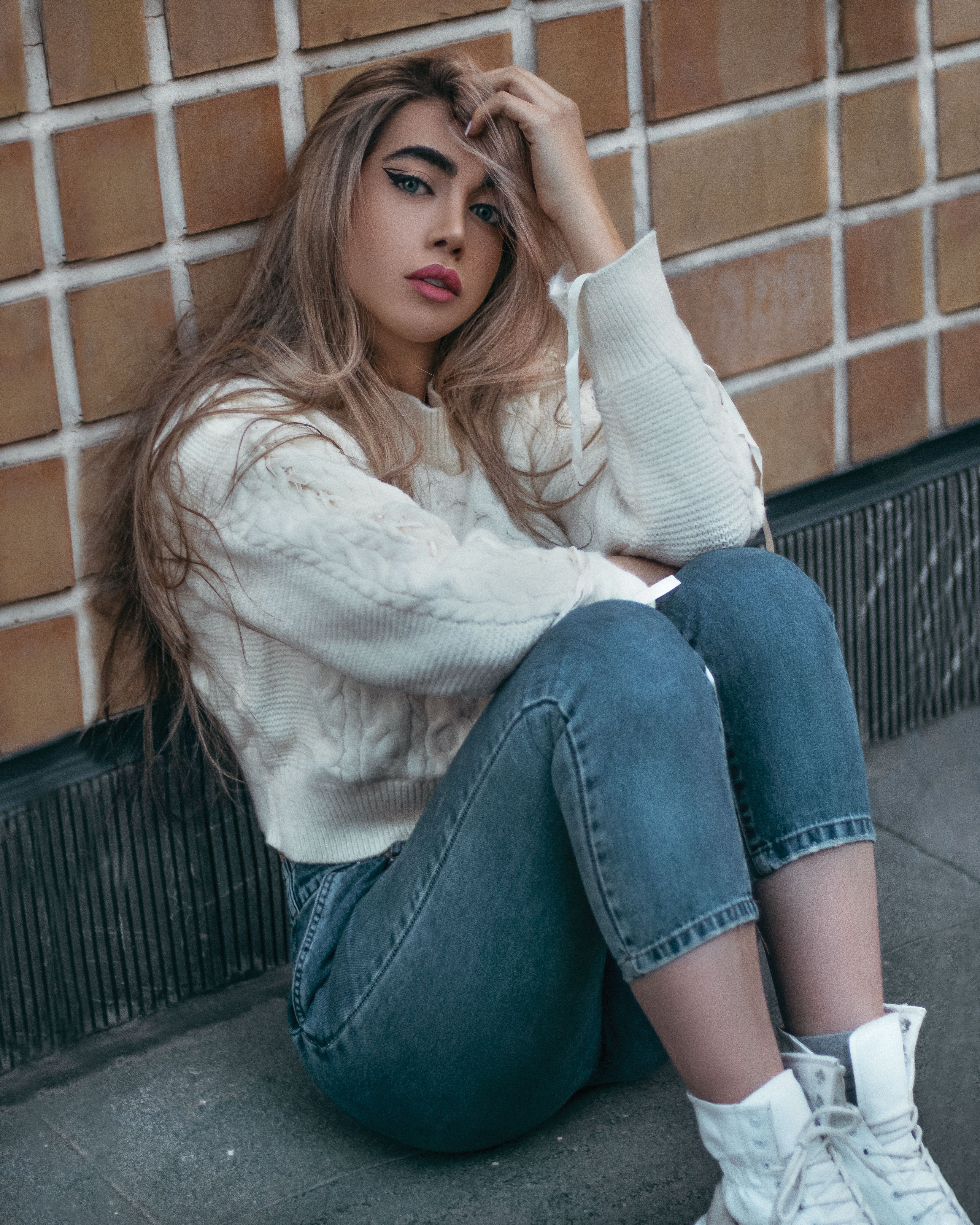 woman in cozy cream sweater with jeans and gold hoops