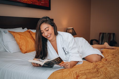 Smiling Brunette Woman Reading Book on Bed