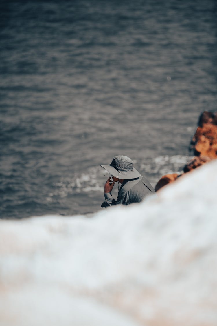 Person In Travel Clothing Sitting On Cliff