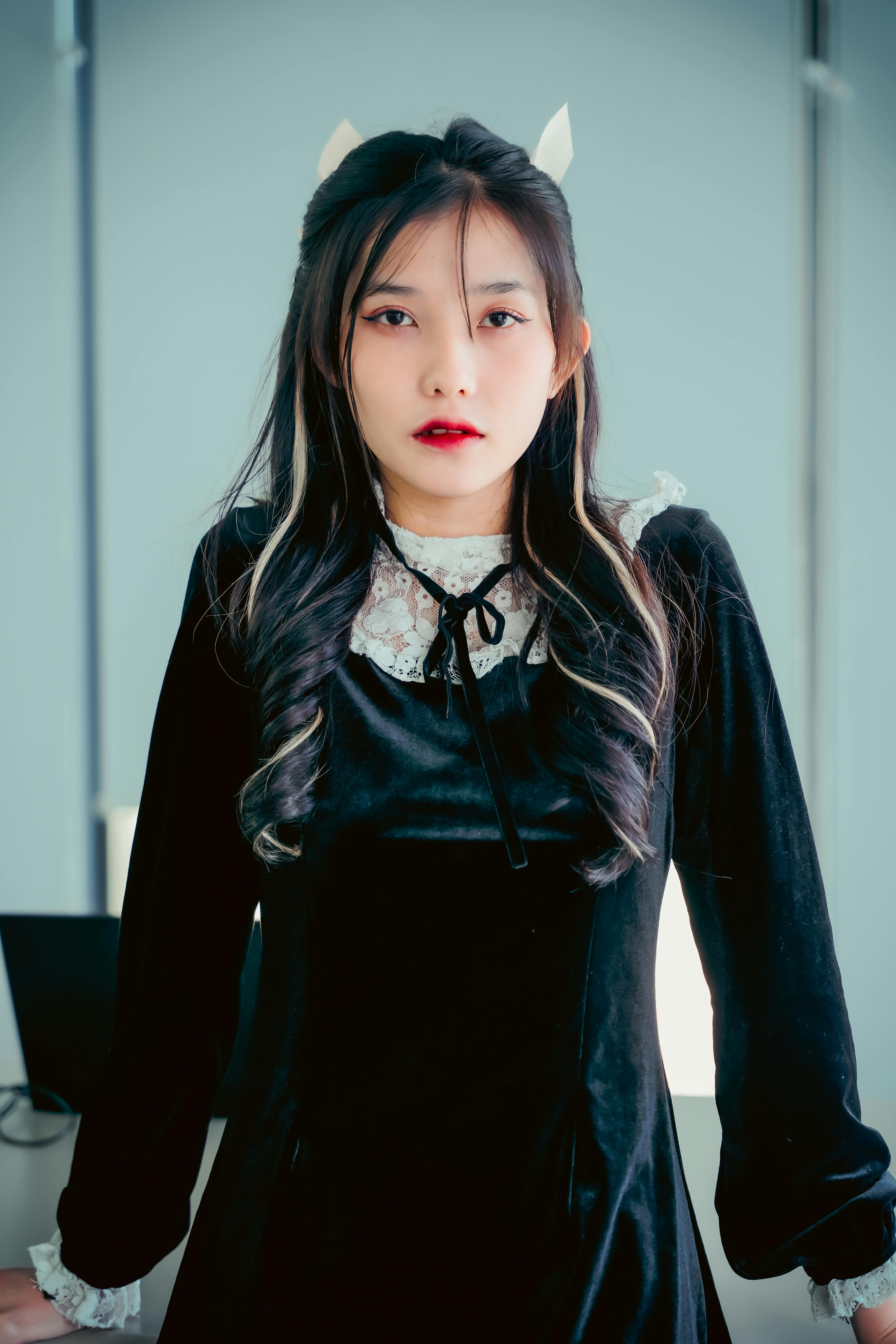 Elegant woman with long hair in black gothic dress posing indoors. Fashion photo.