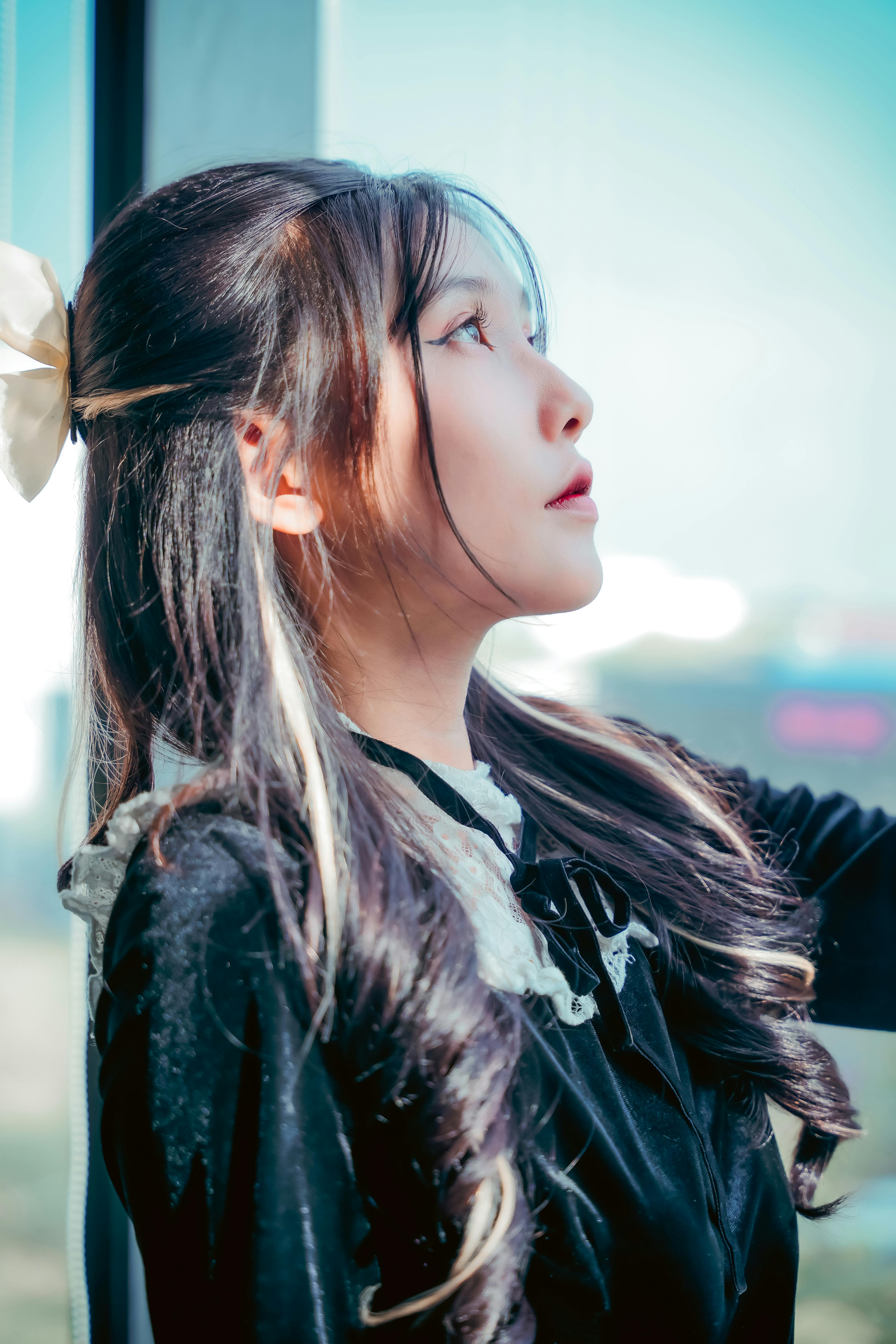 Portrait of a woman with long hair and black dress gazing outside. Captures elegance and thoughtful 