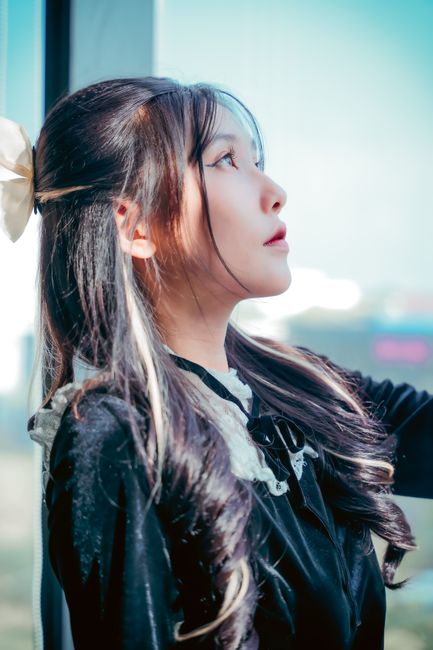 Portrait of a woman with long hair and black dress gazing outside. Captures elegance and thoughtful
