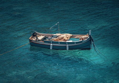 Free A tranquil scene of a single boat moored in clear turquoise waters, offering a peaceful marine escape. Stock Photo