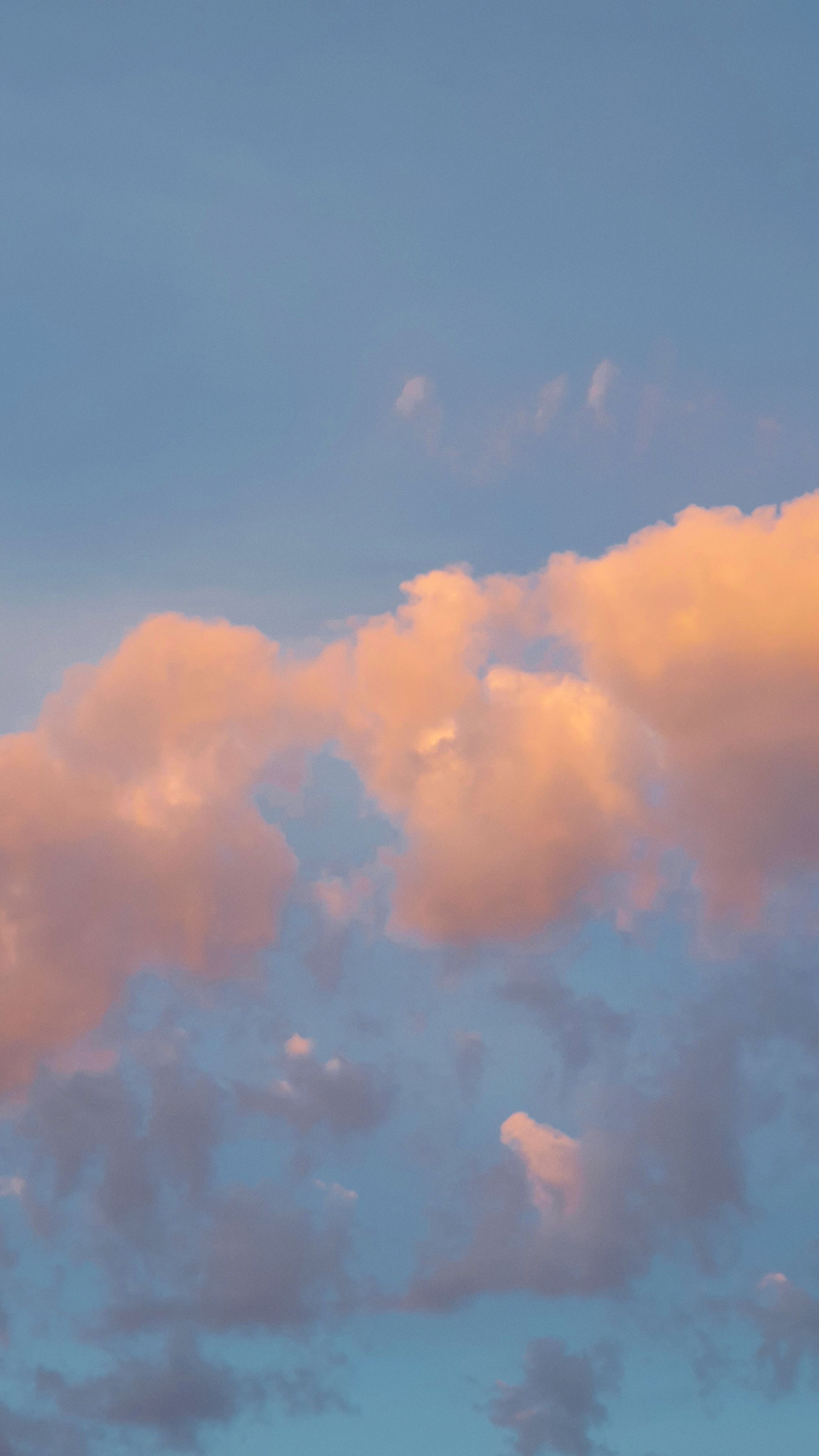 A tranquil vertical shot of pastel clouds against a blue sky, perfect for wallpaper.