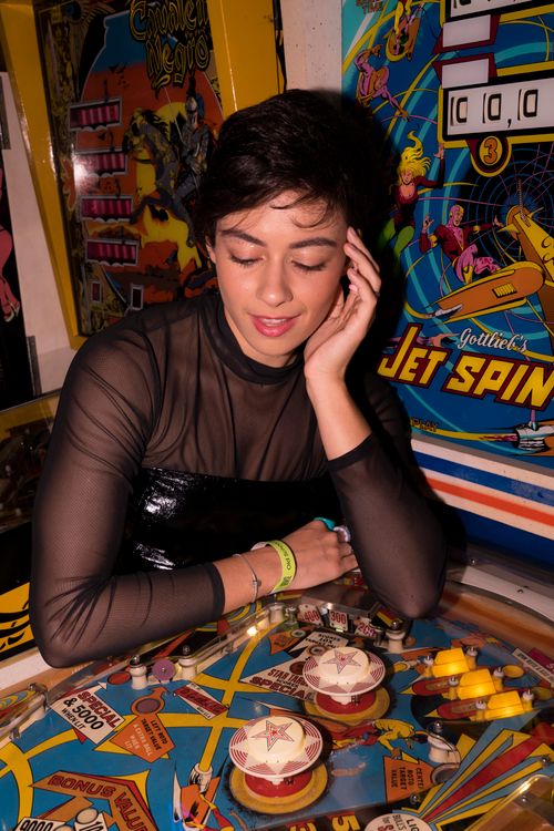 Free A young woman playing a vintage pinball machine at a retro arcade in São Paulo. Stock Photo