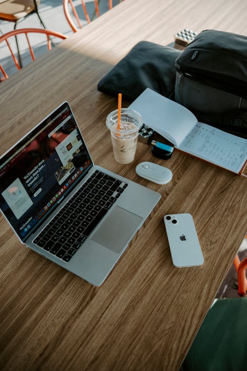 Person Writing On A Notebook Beside Macbook · Free Stock Photo