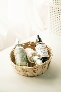 Close-up of fragrance bottles in a woven basket on a white background, bathed in natural light.