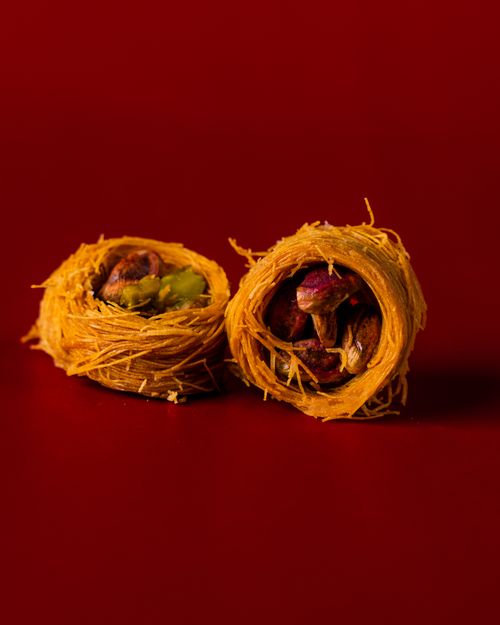 Free Delicious close-up of traditional Turkish pistachio sweets on a rich red background. Stock Photo