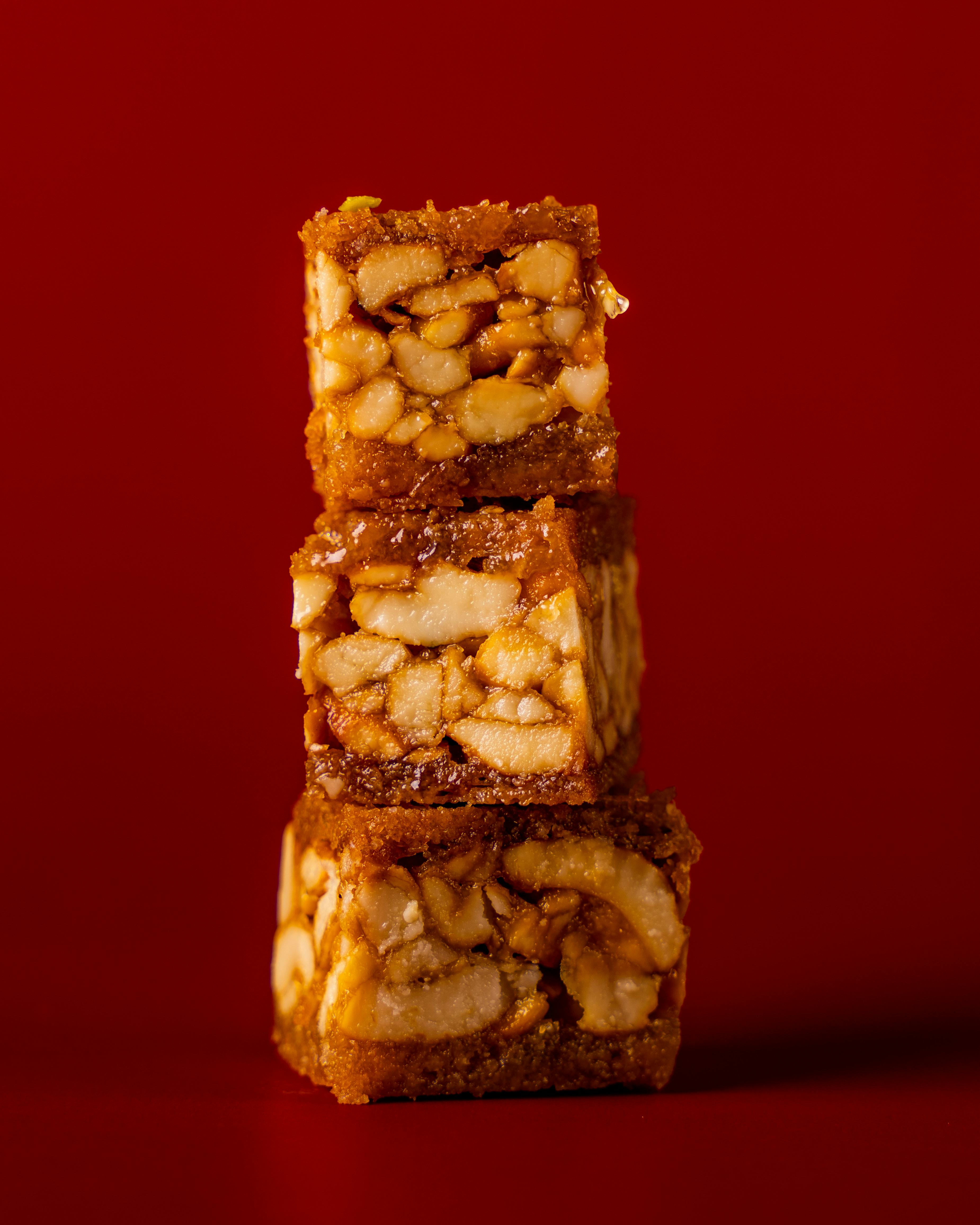 Close-up of stacked Turkish nut bars against a vibrant red backdrop, showcasing textures.