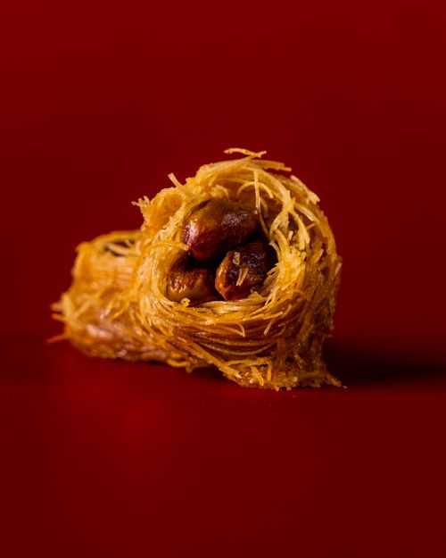 Free Close-up of a sweet baklava dessert in a studio setting with a red background. Stock Photo