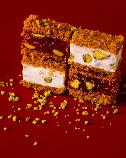 Free Close-up of Turkish pastries with nuts and cream on a deep red background, a delicious dessert option. Stock Photo