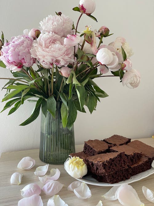 A Bunch of Peonies in a Vase and Chocolate Cake on a Plate 