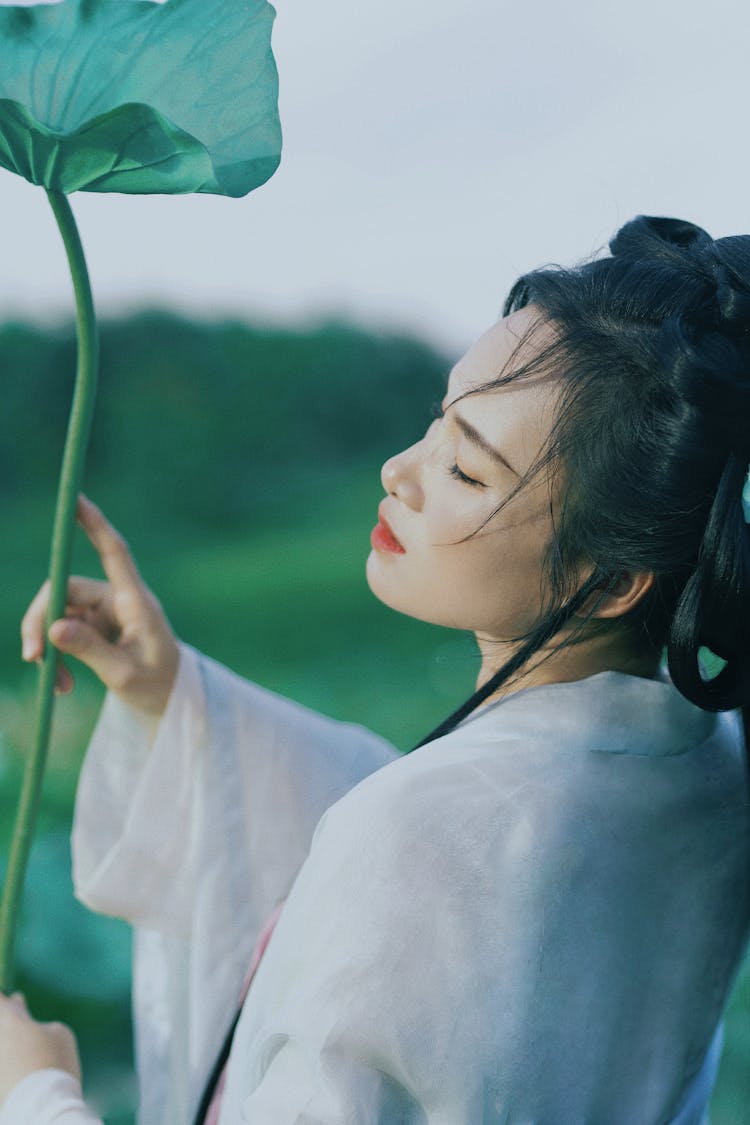 Young Woman In White Traditional Chinese Dress Holding A Lotus Leaf