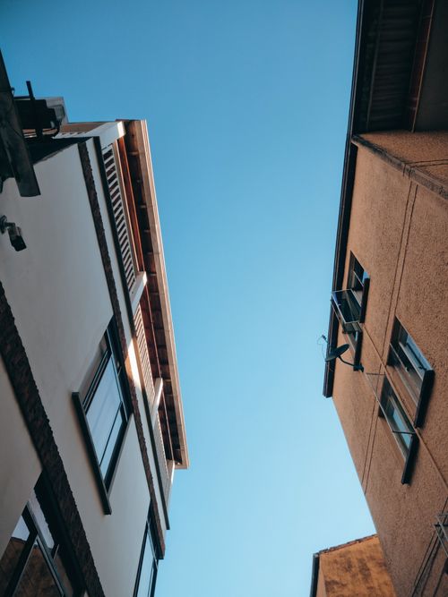 Free Upward view of narrow alleyway between buildings in Bucaramanga, Colombia under a clear blue sky. Stock Photo