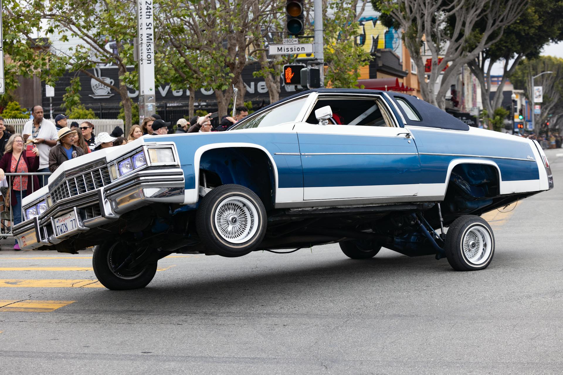 A classic vehicle on hydraulics wows the crowd on a busy city street.