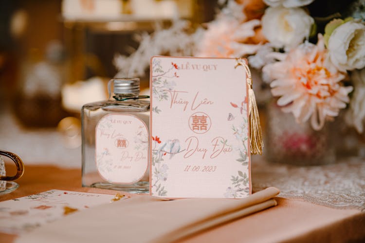 A Wedding Invitation And A Glass Bottle On The Table 