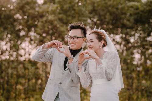 Bride and Groom Making Heart Shapes with Their Hands and Smiling 