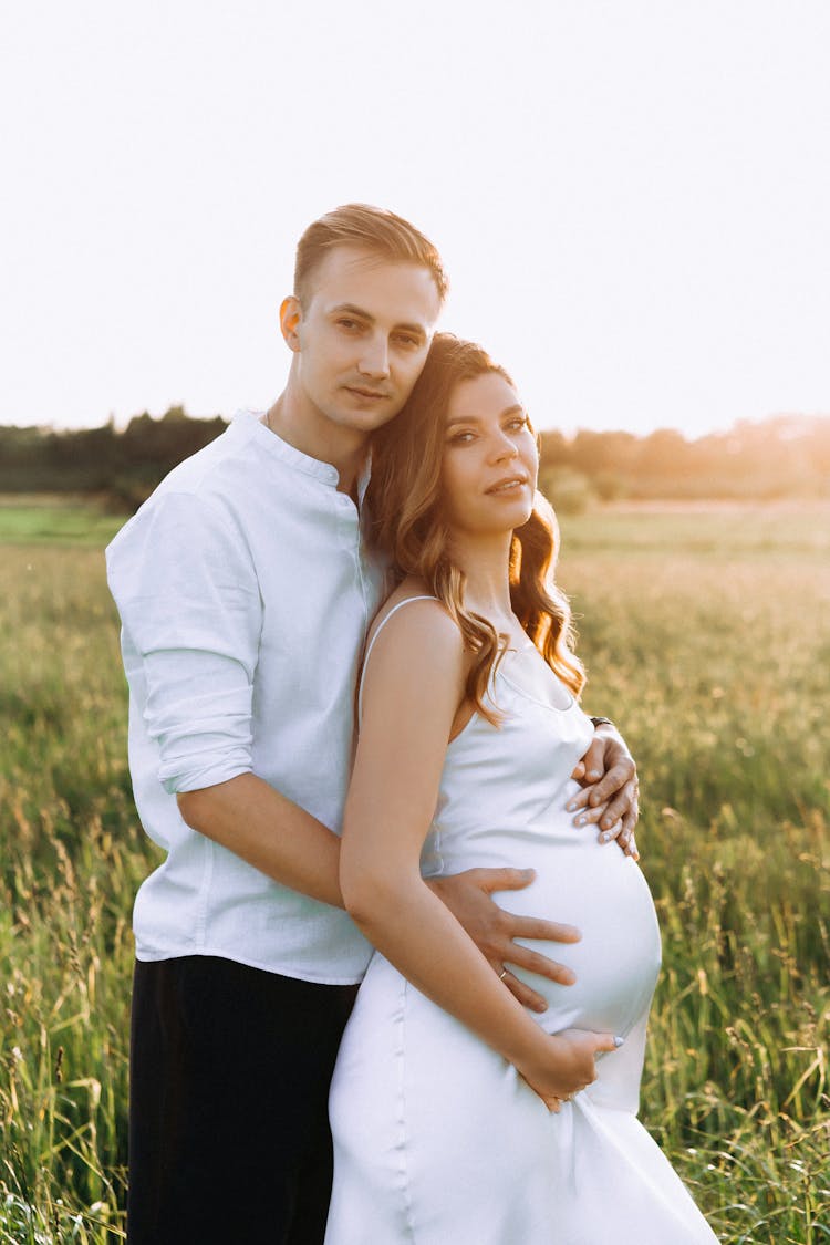 Pregnant Woman And Her Partner Posing Outside 