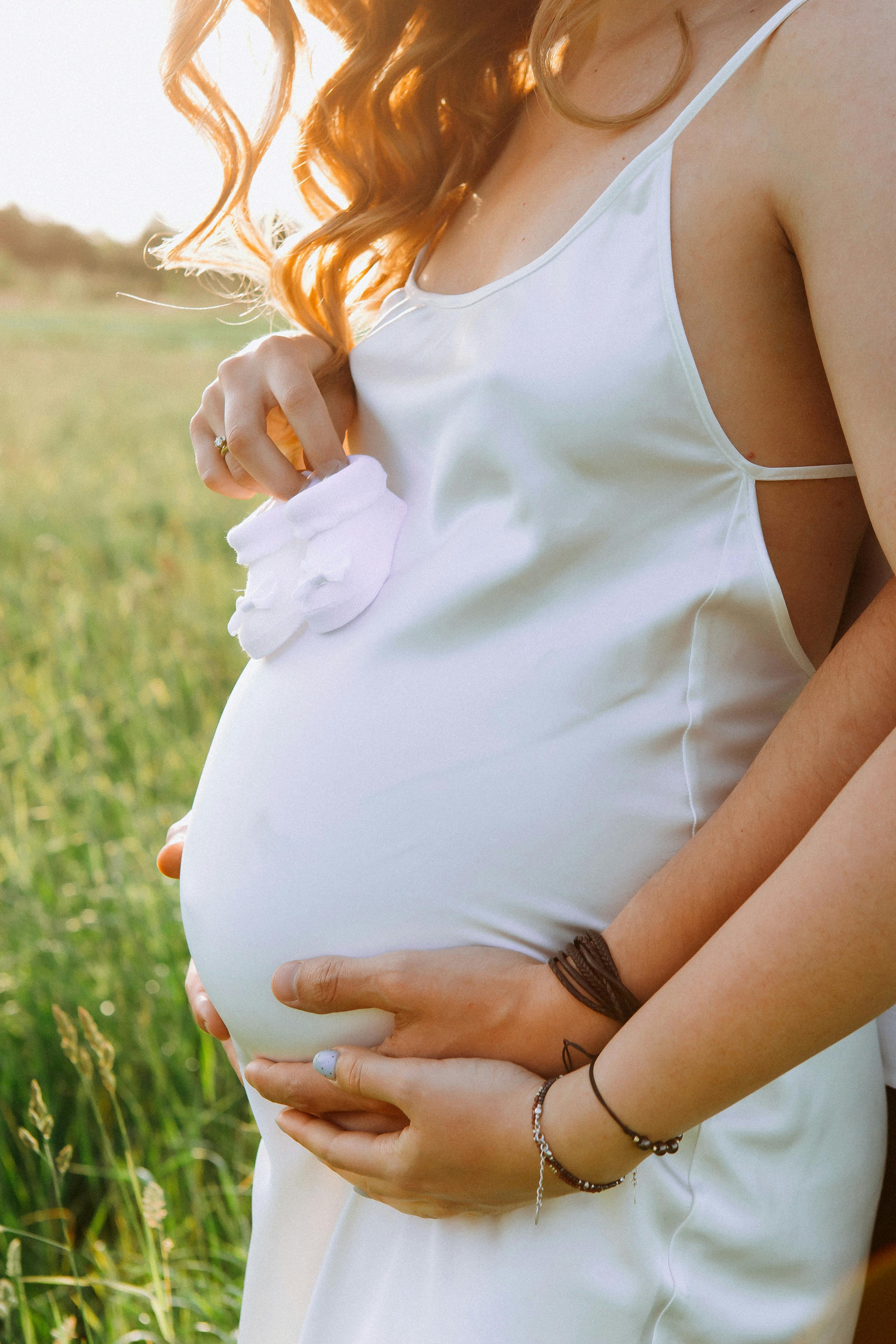 A heartfelt moment captured outdoors highlighting a couple's anticipation and love during a summer pregnancy.