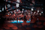 在节日雪花灯光的映照下，人们在室内滑冰场滑冰，营造出欢乐而充满活力的氛围