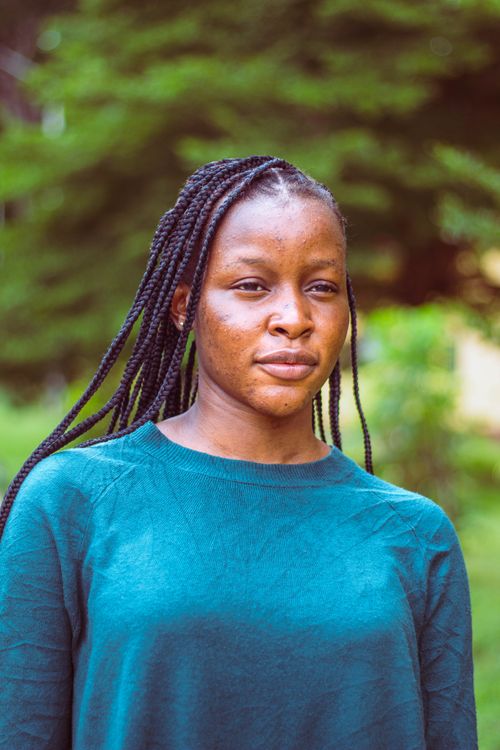 Free A serene portrait of a young woman with braided hair in a blue sweater outdoors. Stock Photo