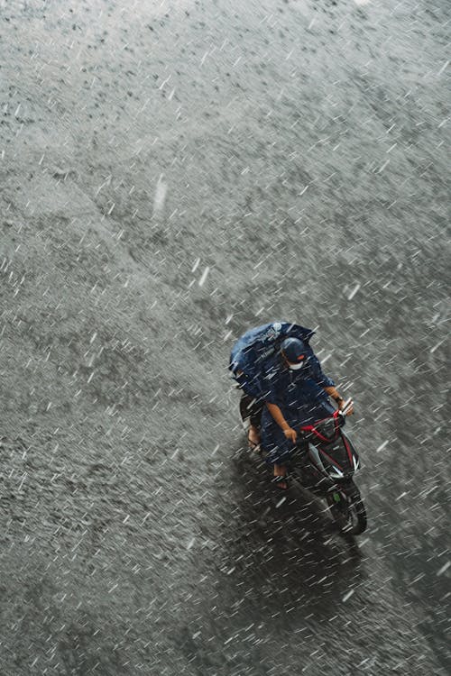 High Angle View of a Person Riding on a Motor Scooter in Heavy Rain 