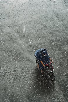 A motorcyclist wearing a raincoat rides through pouring rain in Ho Chi Minh City, Vietnam.