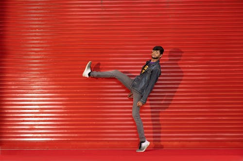 Man in Jean Jacket Posing with Leg Raised