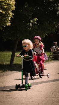 Young children enjoying a sunny day riding bikes and scooters in Trzebnica Park, Poland.