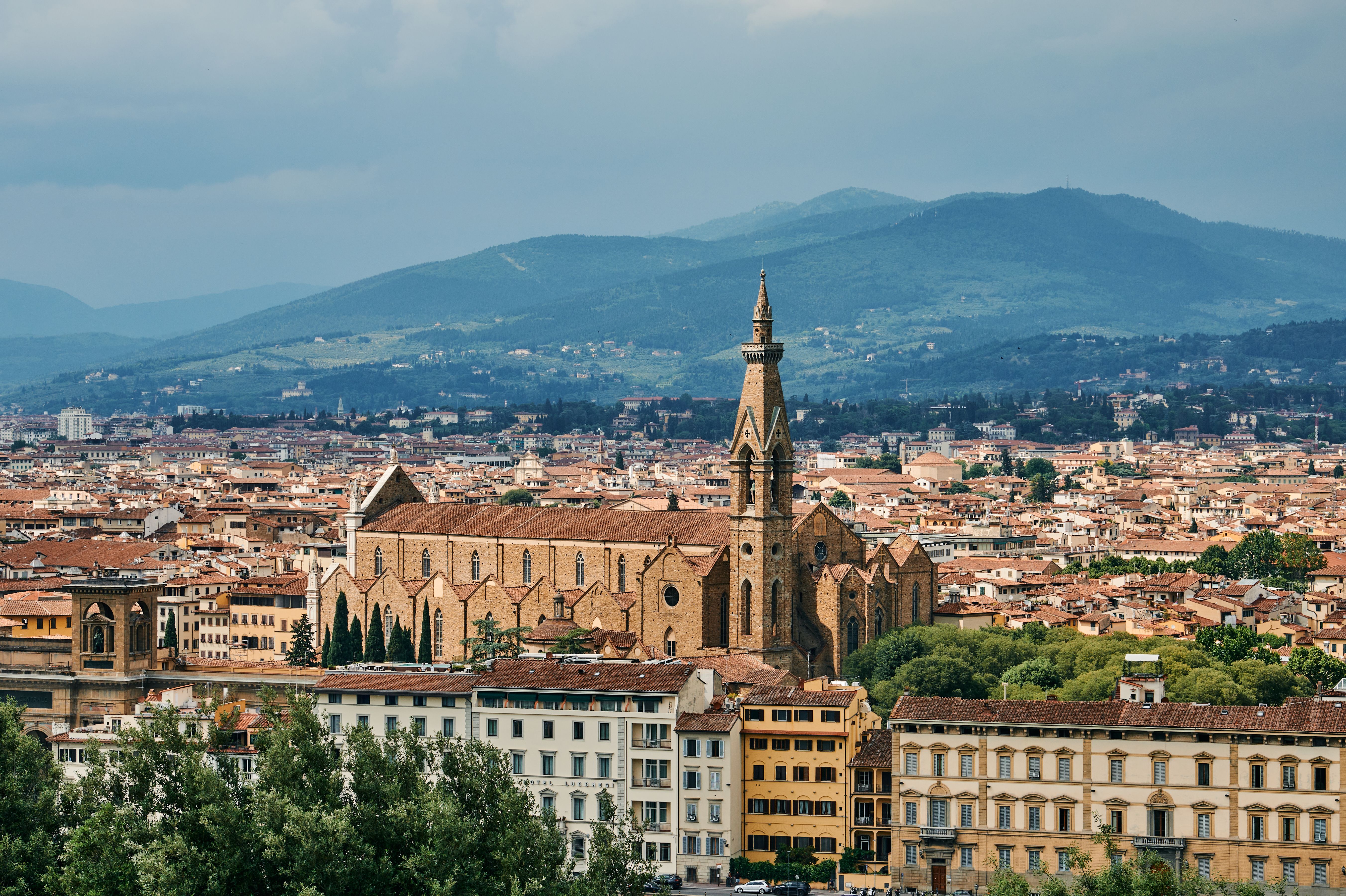 Aerial view of Florence highlighting the iconic Basilica of Santa Croce with scenic hills in the background.
