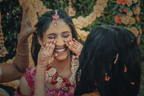 Free Vibrant Indian woman smiling during traditional Haldi ceremony, adorned with flowers and henna. Stock Photo