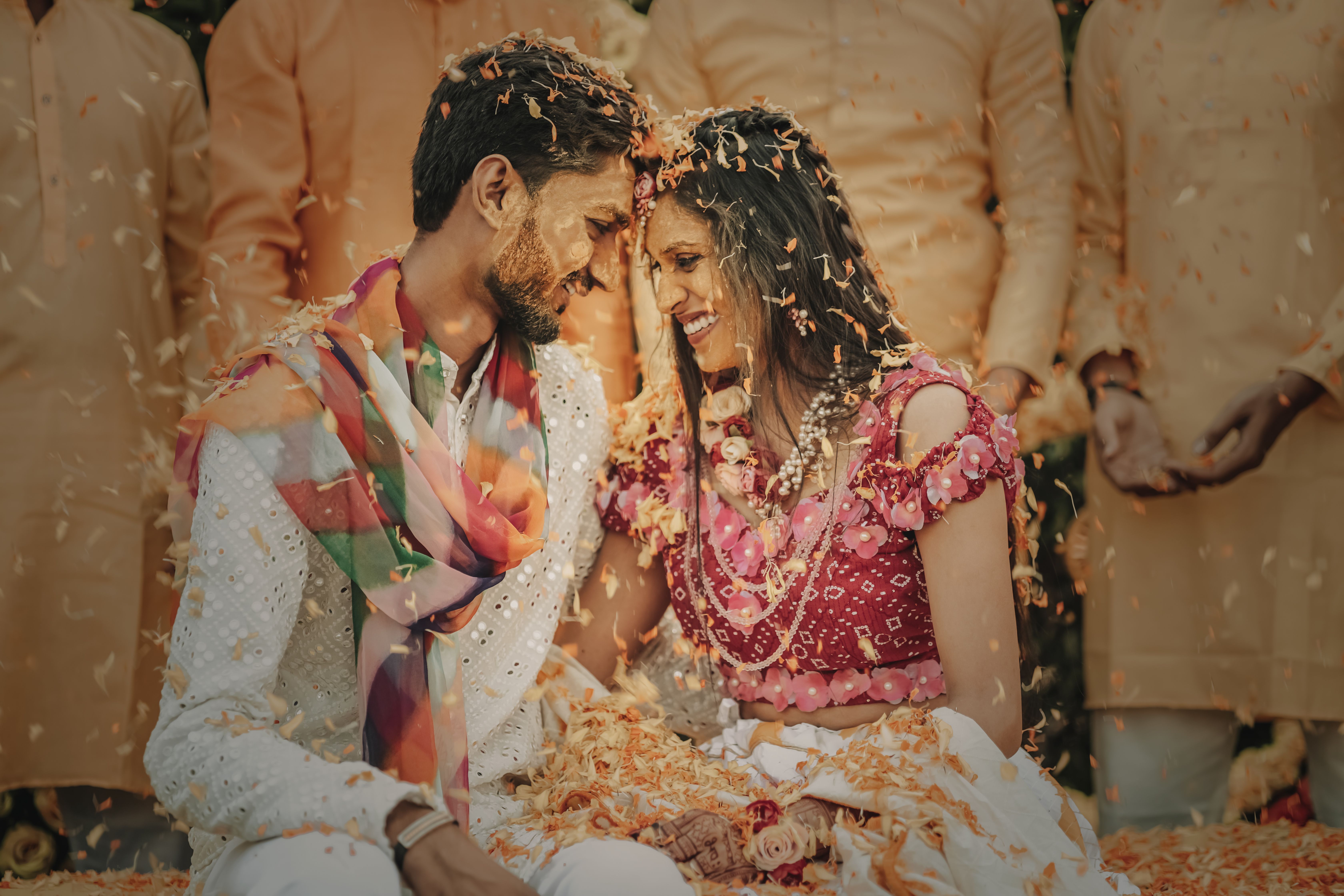 Joyful moment of an Indian couple celebrating their wedding with smiles and flower confetti.