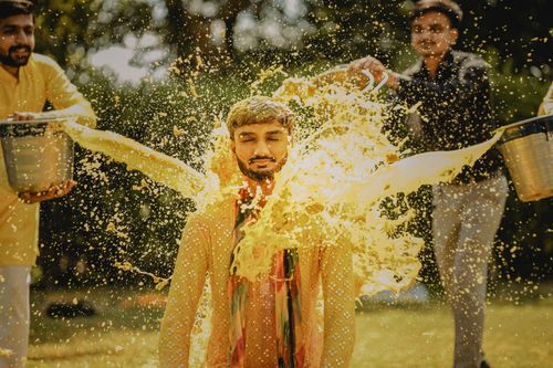 Free Indian man involved in a traditional pre-wedding ritual with vibrant water splashing. Stock Photo