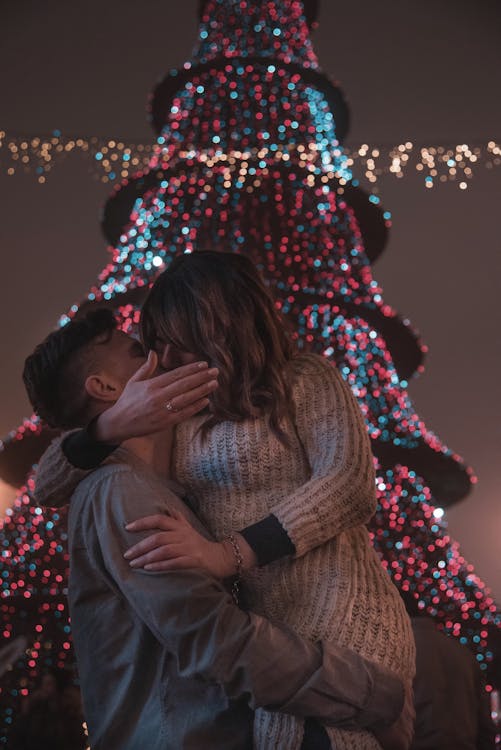 Фотография пары, целующейся перед елкой