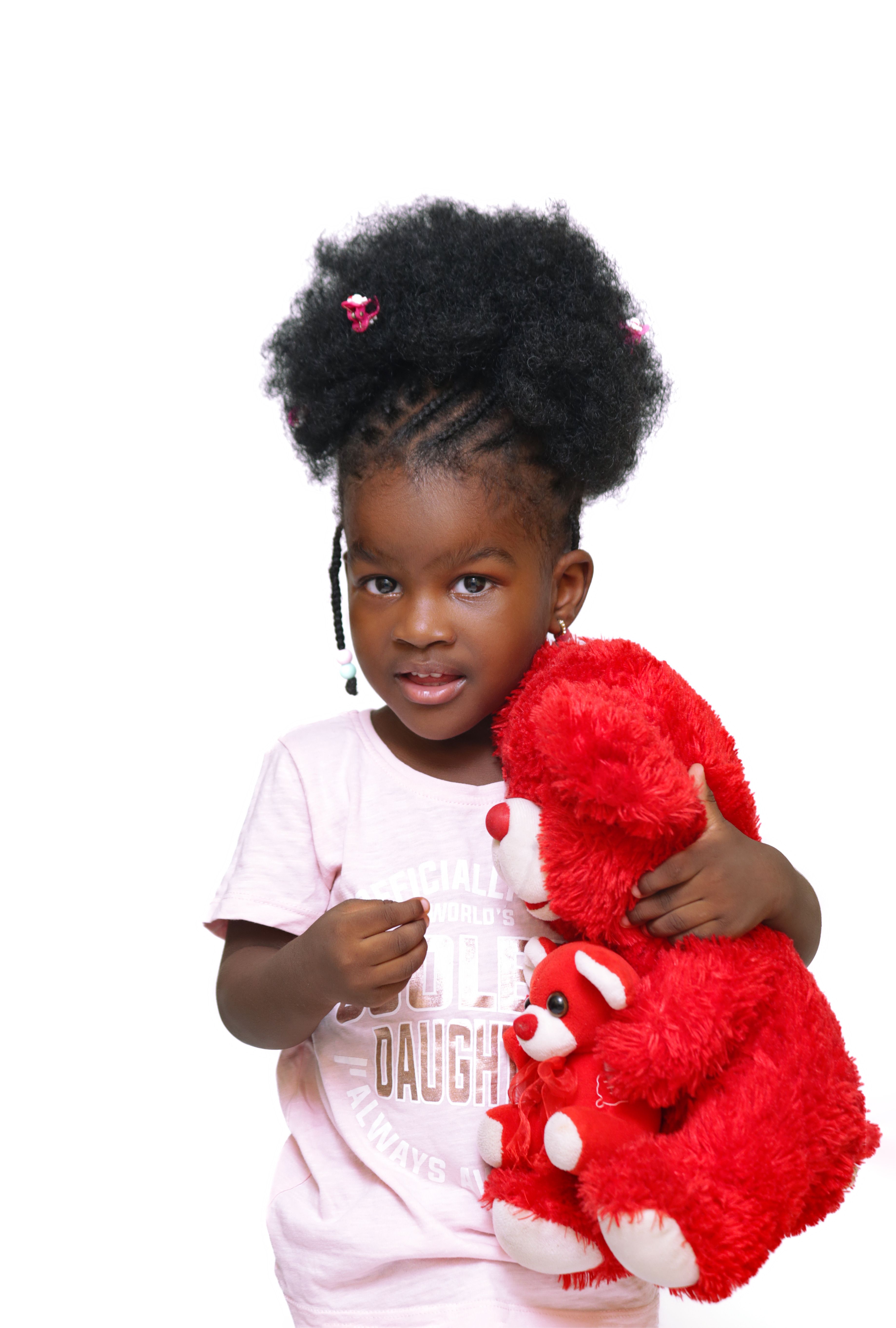 Charming portrait of a little girl cuddling a red teddy bear against a white background.