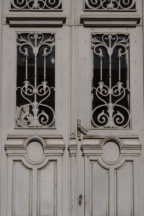 Free Close-up of a vintage door featuring intricate ironwork patterns and aged wood texture. Stock Photo