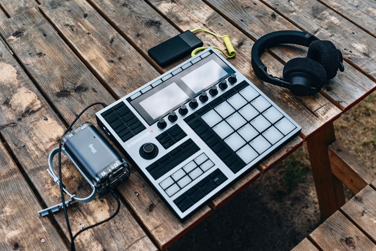 High-angle shot of music production equipment on a wooden table outdoors.