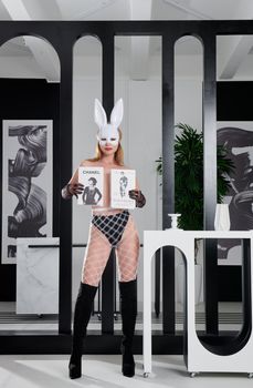 A woman posing indoors in a bold rabbit mask and lingerie, embodying fashion and seduction.