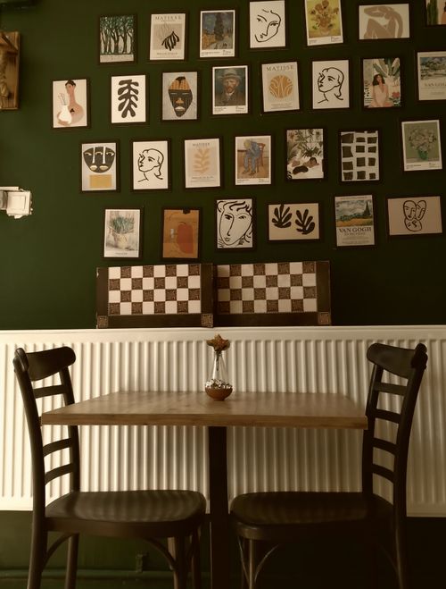 Free Charming café scene with a wooden table, two chairs, and artistic wall decorations. Stock Photo