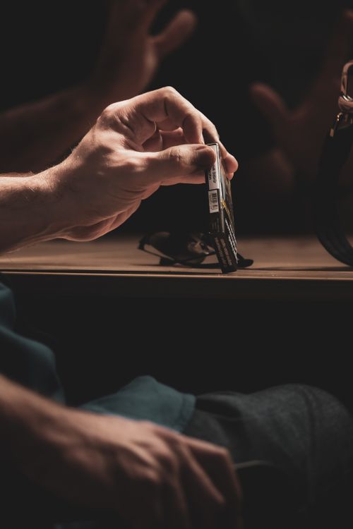 Free A hand holding a cigarette pack in moody, dim lighting, symbolizing habit and addiction. Stock Photo