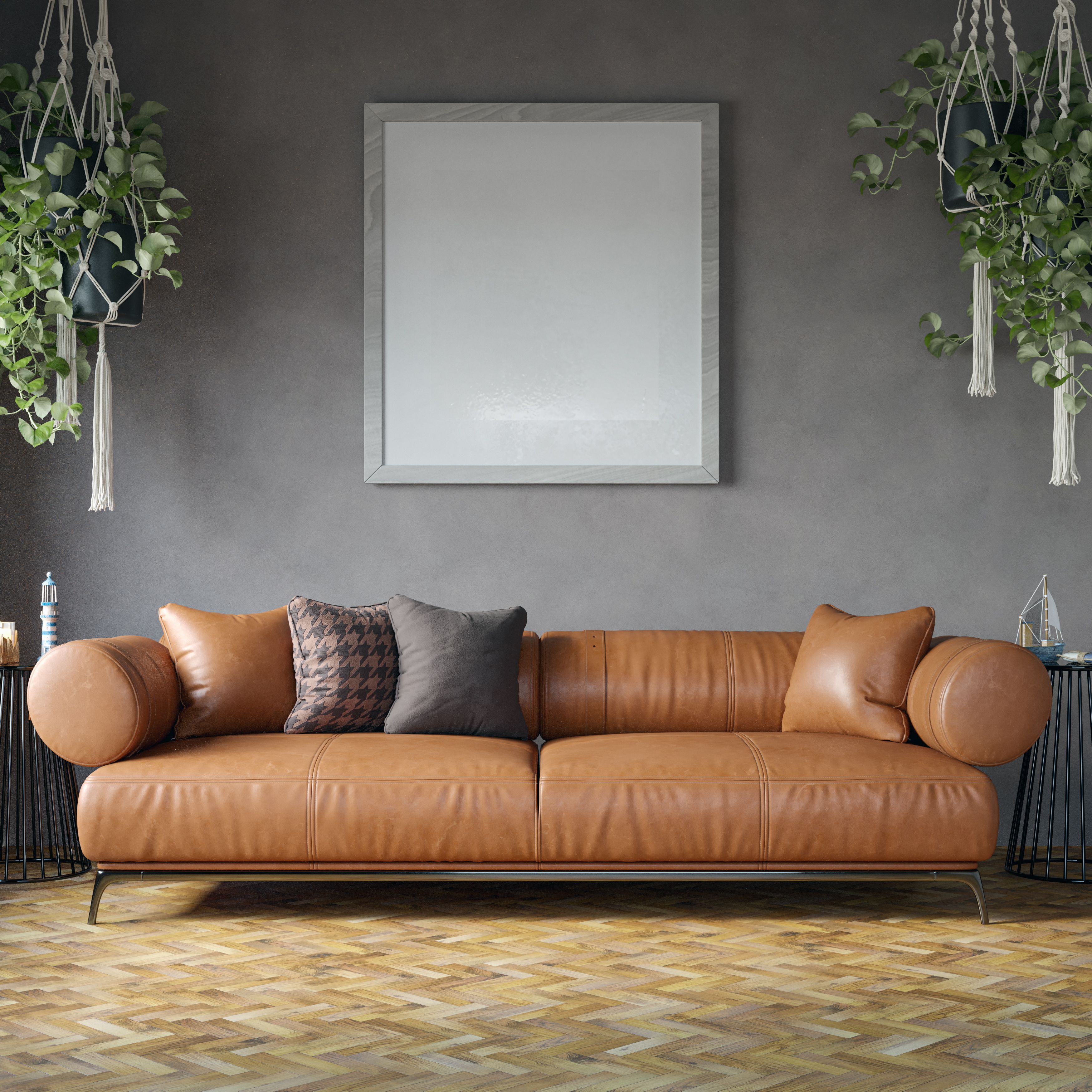 Elegant leather sofa with pillows in a stylish living room featuring hanging plants and a blank frame.