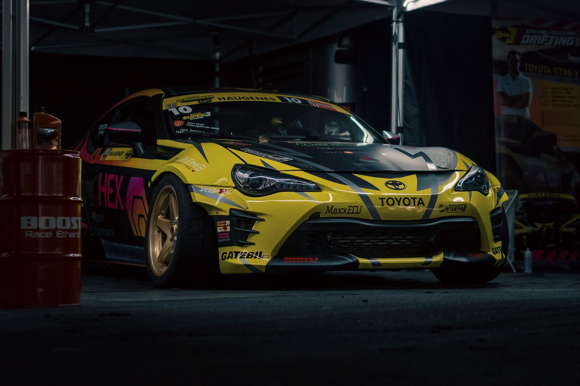 Dynamic shot of a Toyota sports car ready for racing, parked in a garage with vibrant decals.