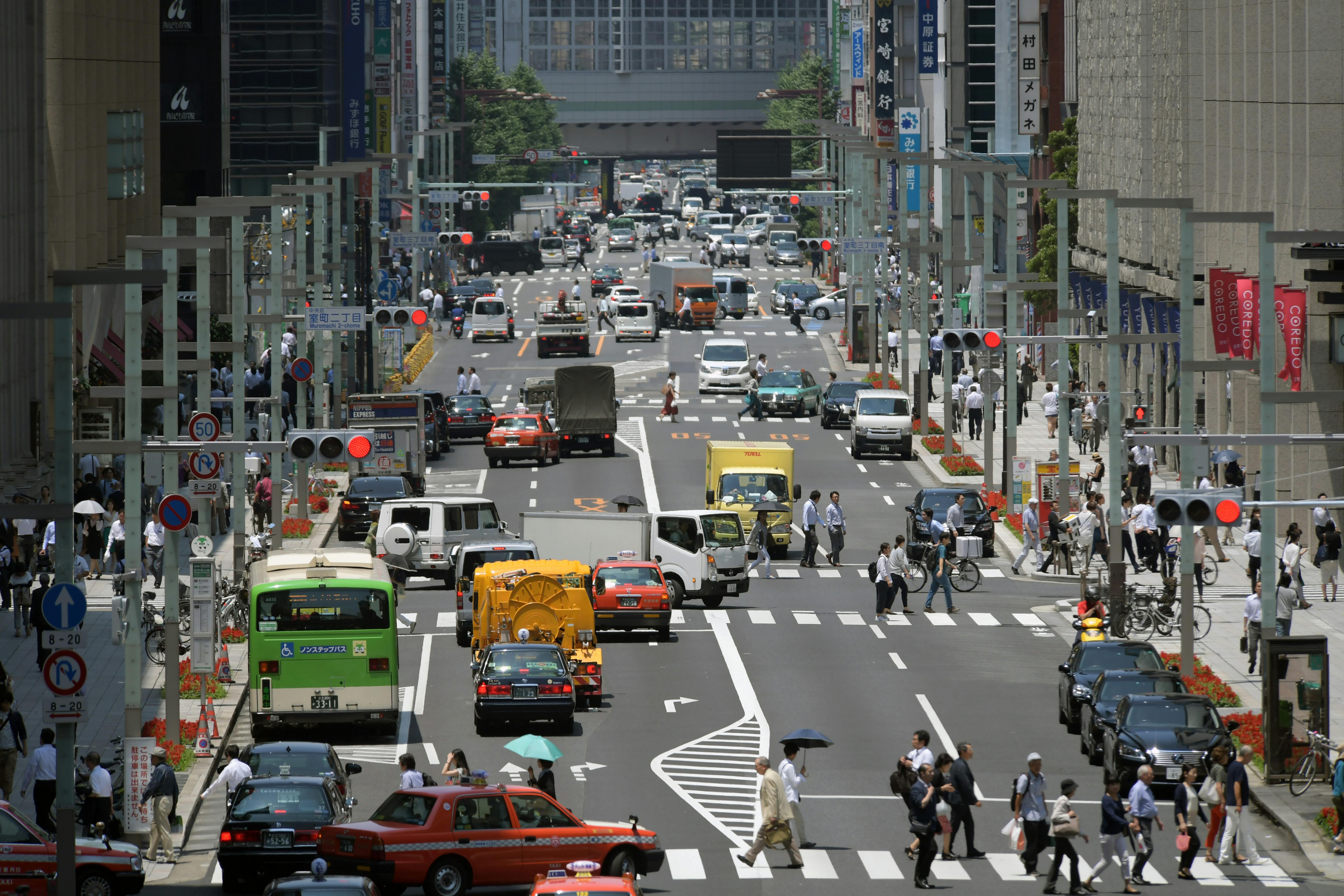 A bustling view of Chuo City, Tokyo's vibrant streets filled with traffic and pedestrians during the day.
